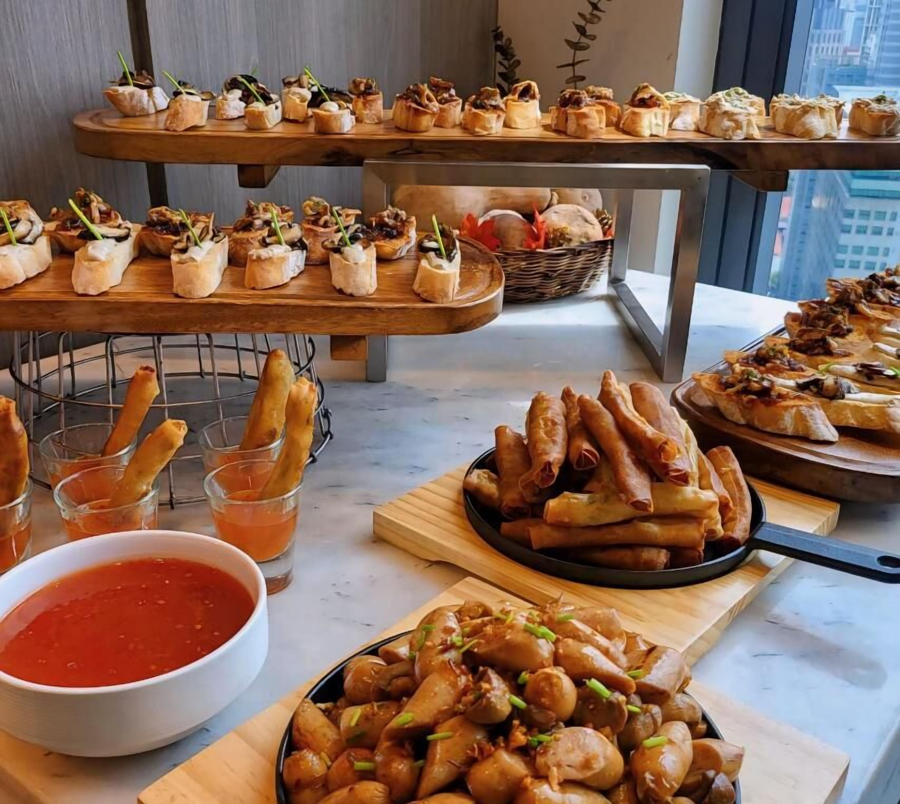 A buffet table with various dishes including appetizers, breadsticks, and a bowl of sauce.