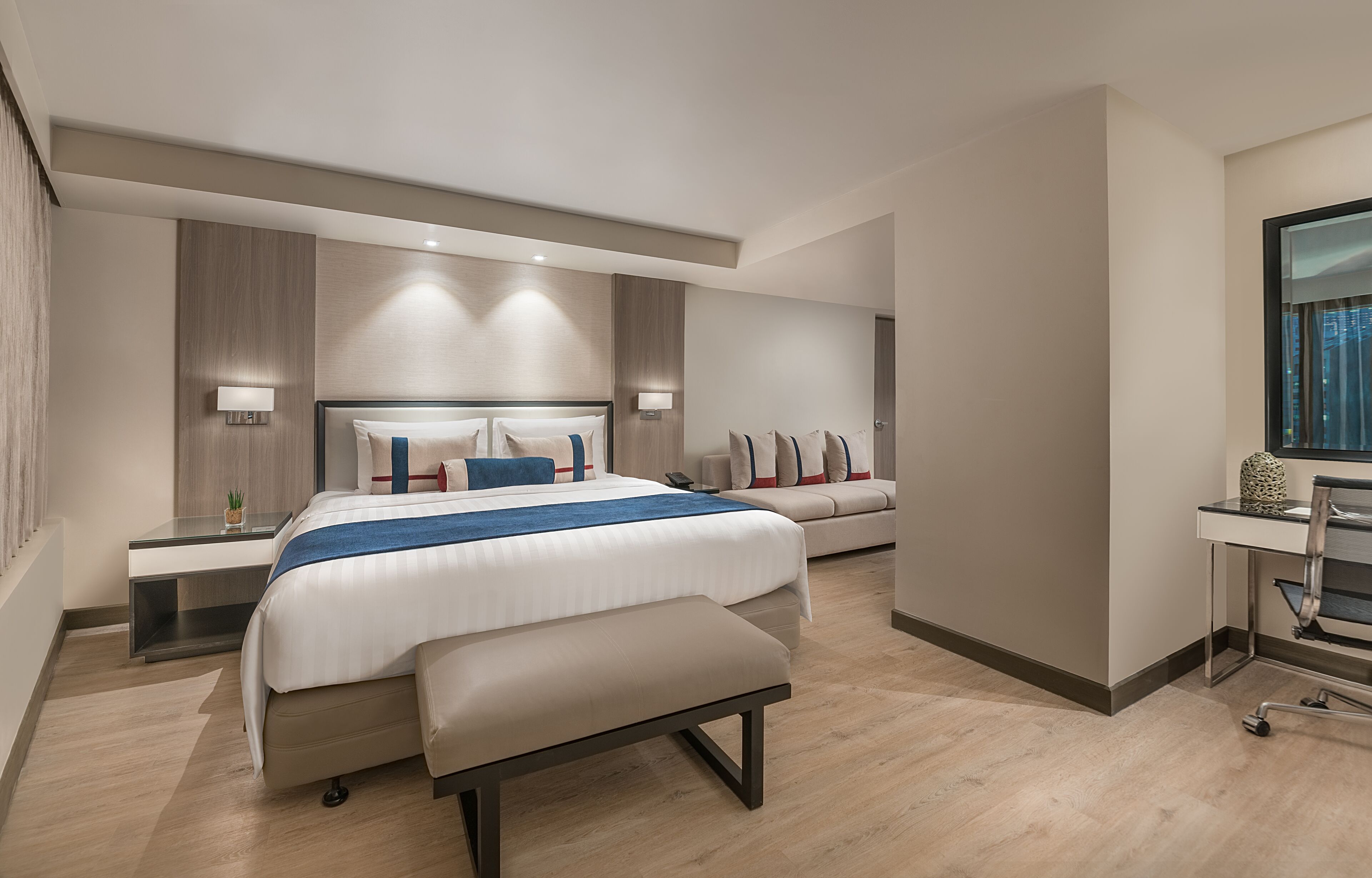 Una habitación de hotel moderna con una cama grande, un escritorio y una silla, además de un ventanal.