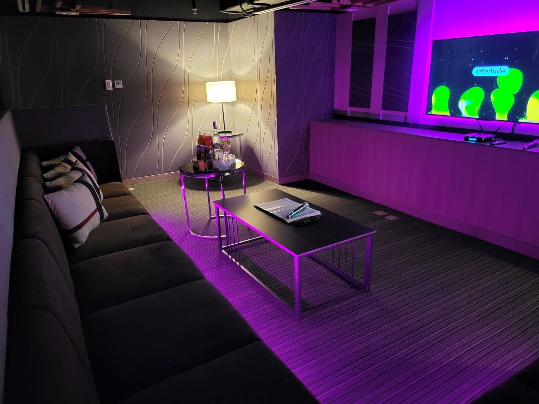 Una sala de estar moderna con un sofá, una mesita de centro y una pantalla de televisión que muestra 'Interlude'.