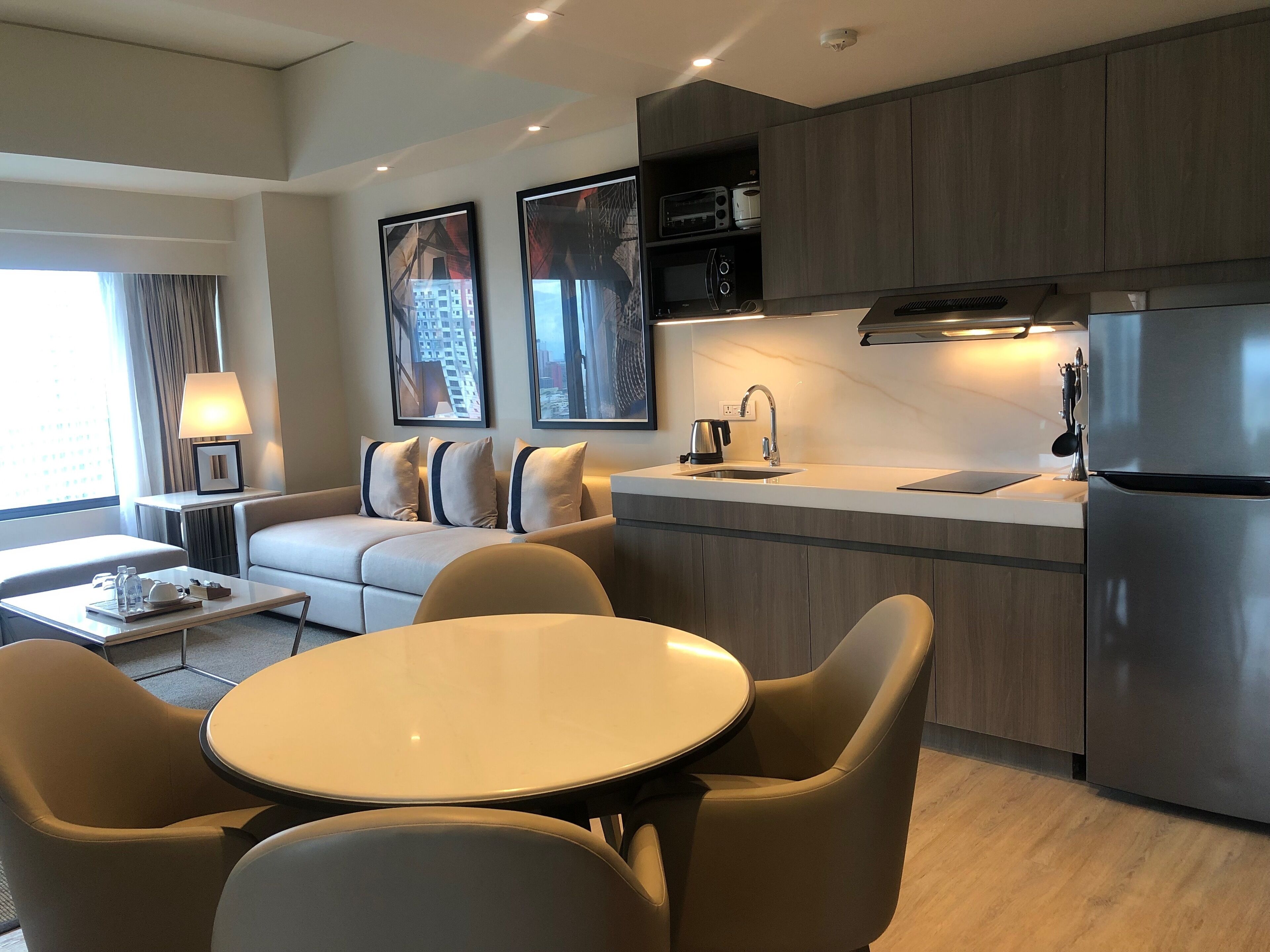 A modern kitchen with a built-in oven, microwave, and refrigerator. There is a dining area with a round table and chairs.