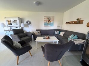 A living room with a grey sofa, two armchairs, a coffee table, and a fireplace.