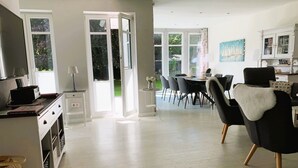Un amplio espacio de estar con una mesa de comedor, sillas y una cocina al fondo.