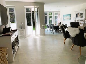 Un amplio espacio de estar con una mesa de comedor, sillas y una cocina al fondo.