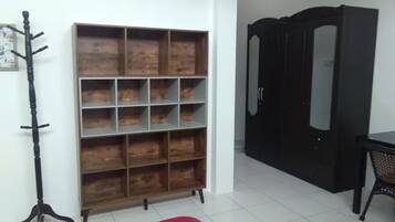 Una habitación con estantería de madera, perchero, armario y alfombra estampada.