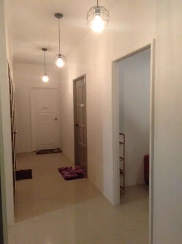 A hallway with two doors, a light fixture, and a small rug. - Co. Living Suite (Bandar Seri Begawan)