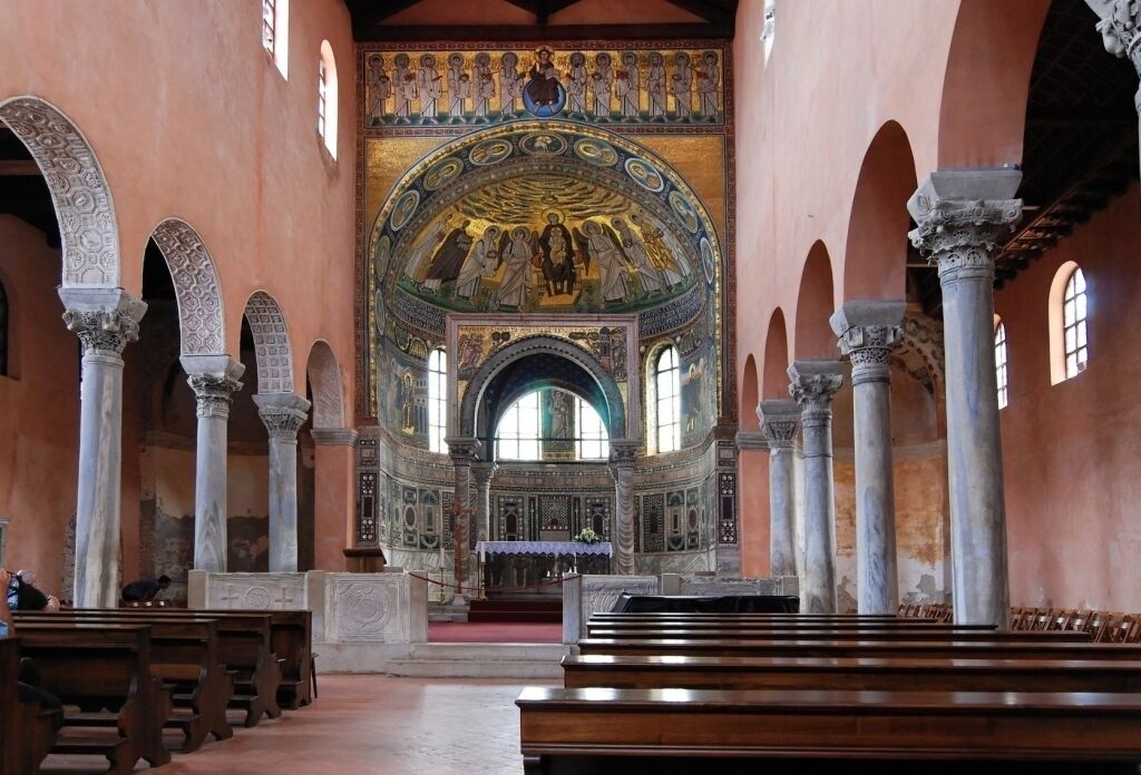Un intérieur caractérisé par de hauts plafonds, des colonnes en arc de cercle et une mosaïque centrale.