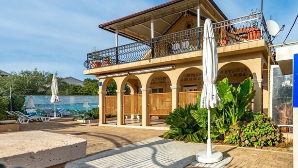 A two-story building with a balcony, outdoor seating, and a pool area.