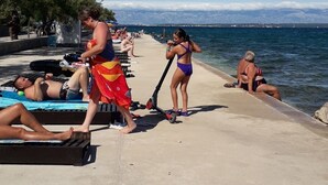 A pier with people sunbathing and swimming.