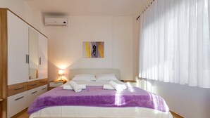 A bedroom with a bed, a wardrobe, a nightstand, a lamp, and a painting on the wall.