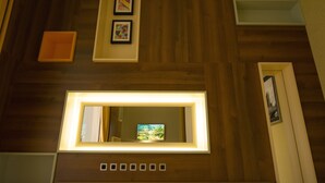 Eine Decke mit Holzbeschlägen, gerahmten Kunstwerken und einem beleuchteten Spiegel.