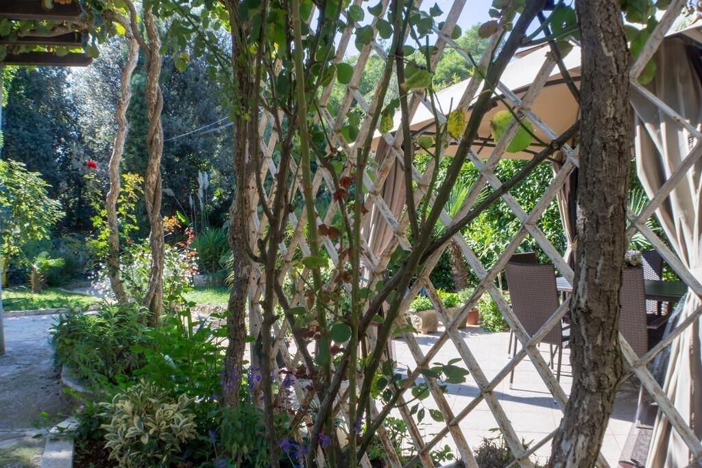 Un jardin agrémenté d’une structure en treillis de bois, d’un sentier et de mobilier d’extérieur.