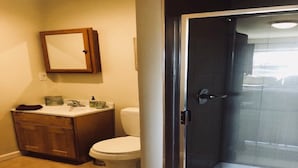 Un baño con inodoro, lavamanos y ducha con mampara de vidrio.