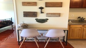 Un comedor con una mesa de madera, dos sillas blancas y una pared decorada con varias placas de madera y un adorno con forma de oso de metal.
