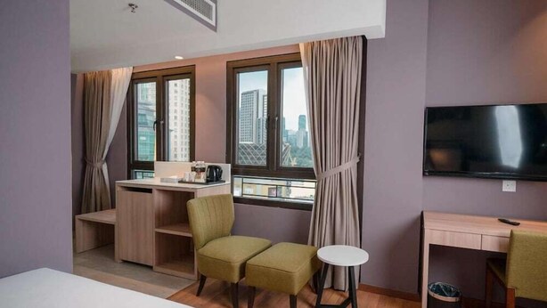 A hotel room with a bed, a desk, a chair, a small table, a TV, and a window with curtains. - MPALACE HOTEL KUALA LUMPUR (Kuala Lumpur)