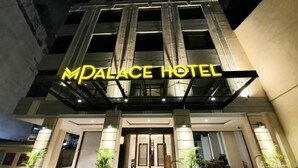 The exterior of the MPALACE HOTEL with a prominent illuminated sign, a modern entrance, and potted plants at the entrance. - MPALACE HOTEL KUALA LUMPUR (Kuala Lumpur)