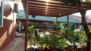 A covered patio area with outdoor furniture, potted plants, and a bicycle. - D'Lima Beach Inn (Langkawi)