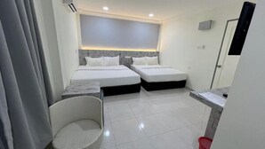 A hotel room with two beds, a small seating area, and a bathroom. - D'Lima Beach Inn (Langkawi)