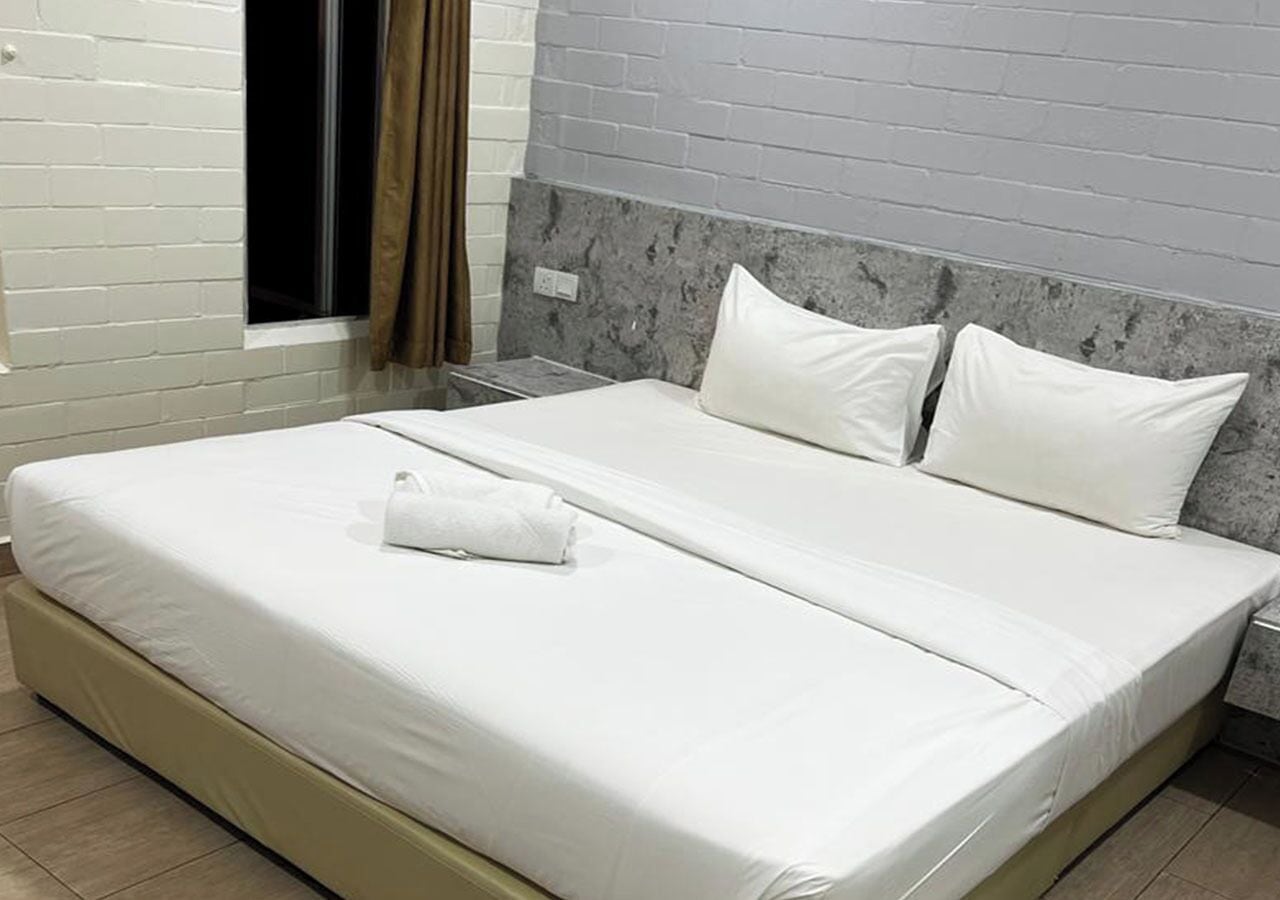 A bed with white bedding, a pillow, and a folded towel.