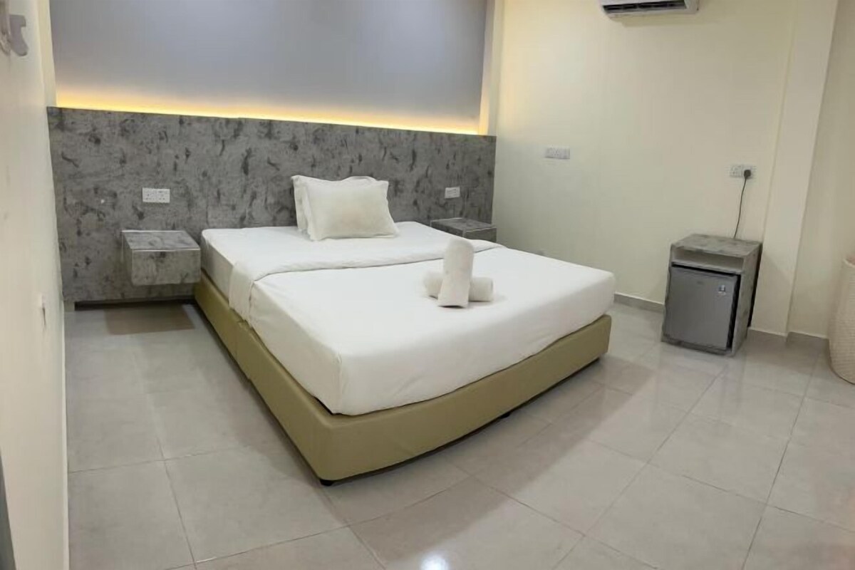 A modern bedroom with a large bed, a marble headboard, a bedside table, and a small storage unit.