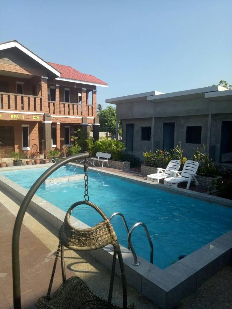 A swimming pool with lounge chairs and a building with a red roof.