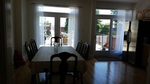 Ein Essbereich mit Tisch und Stühlen, einer Vase und Blick durch Glastüren nach draußen.