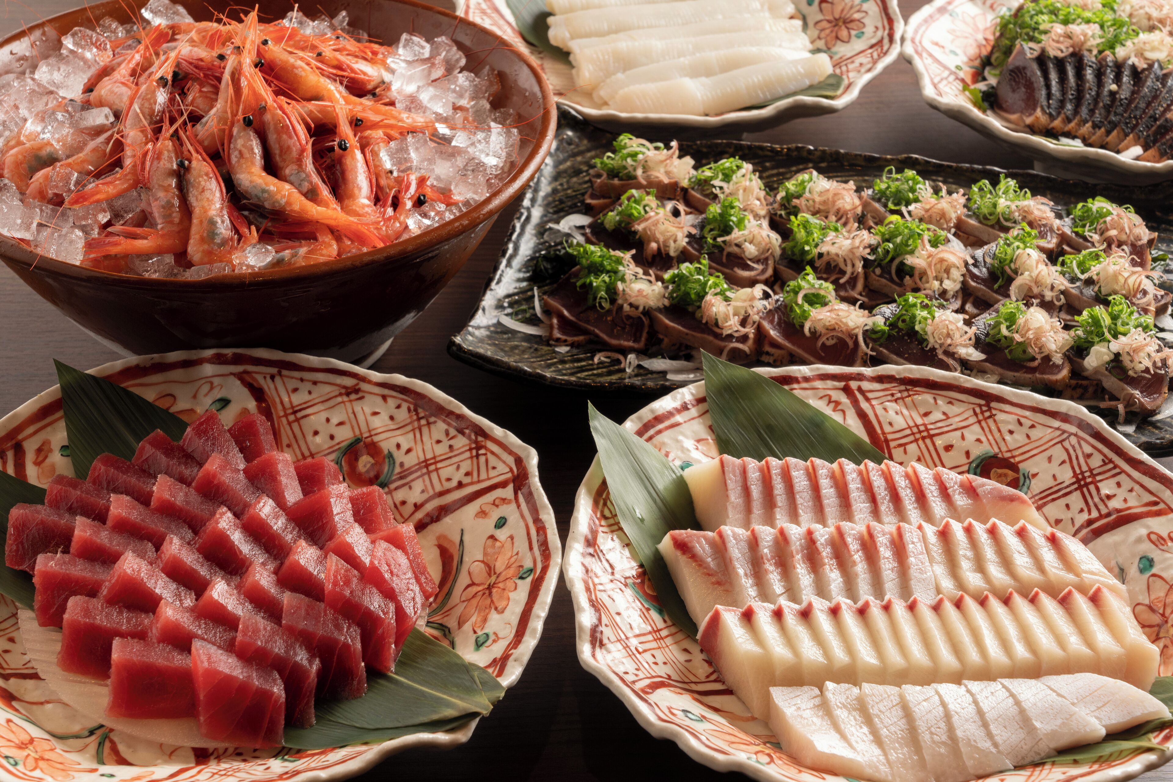 Diverse pietanze di pesce, tra cui sashimi e sushi, disposte su piatti.