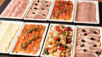 A variety of food platters including sliced meats, cheeses, and vegetables.