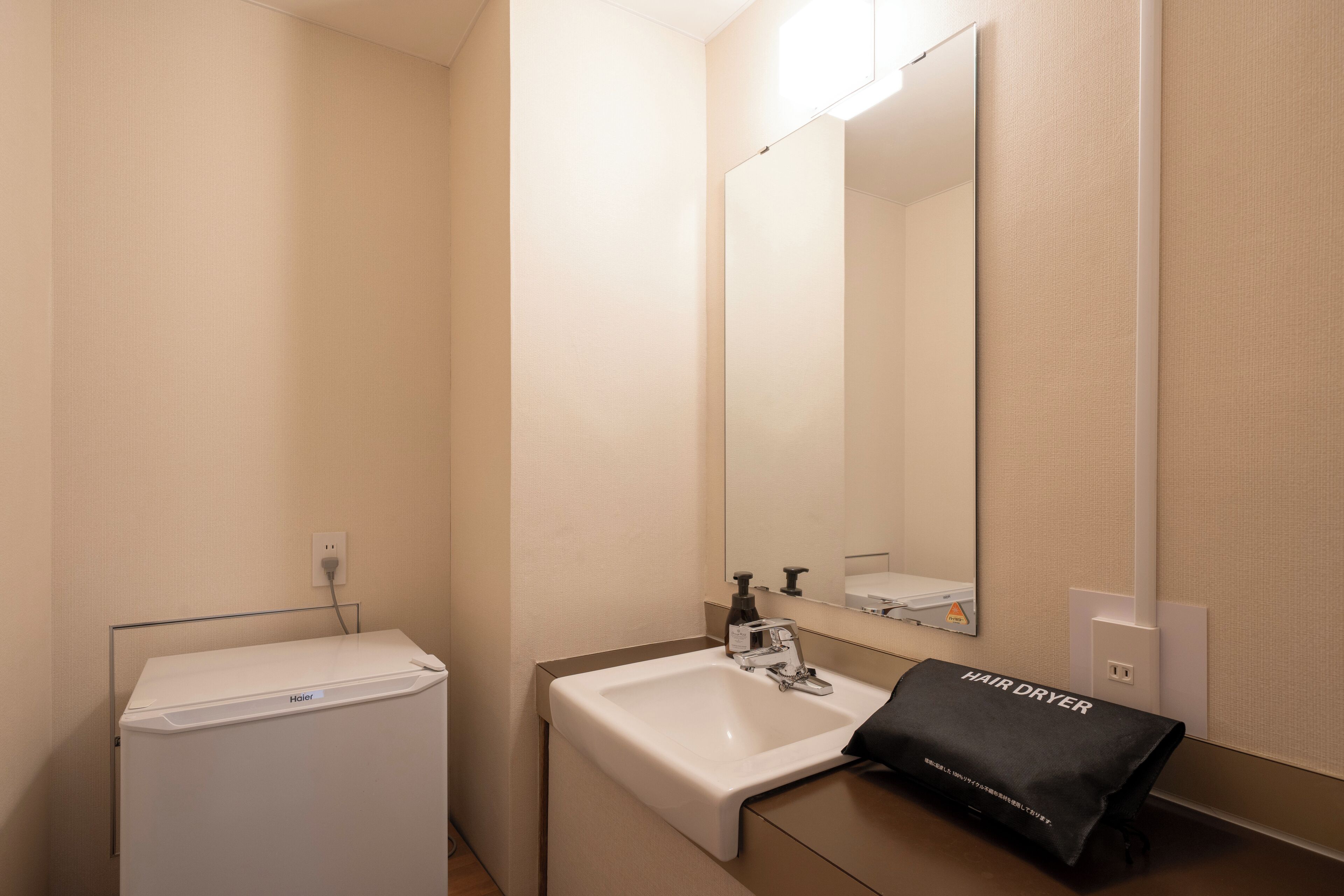 Een badkamer met een witte wasbak, een spiegel en een tas voor een haardroger op het aanrecht.