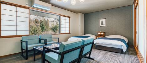 A hotel room with a large window, two beds, a table with chairs, and a ceiling light fixture.