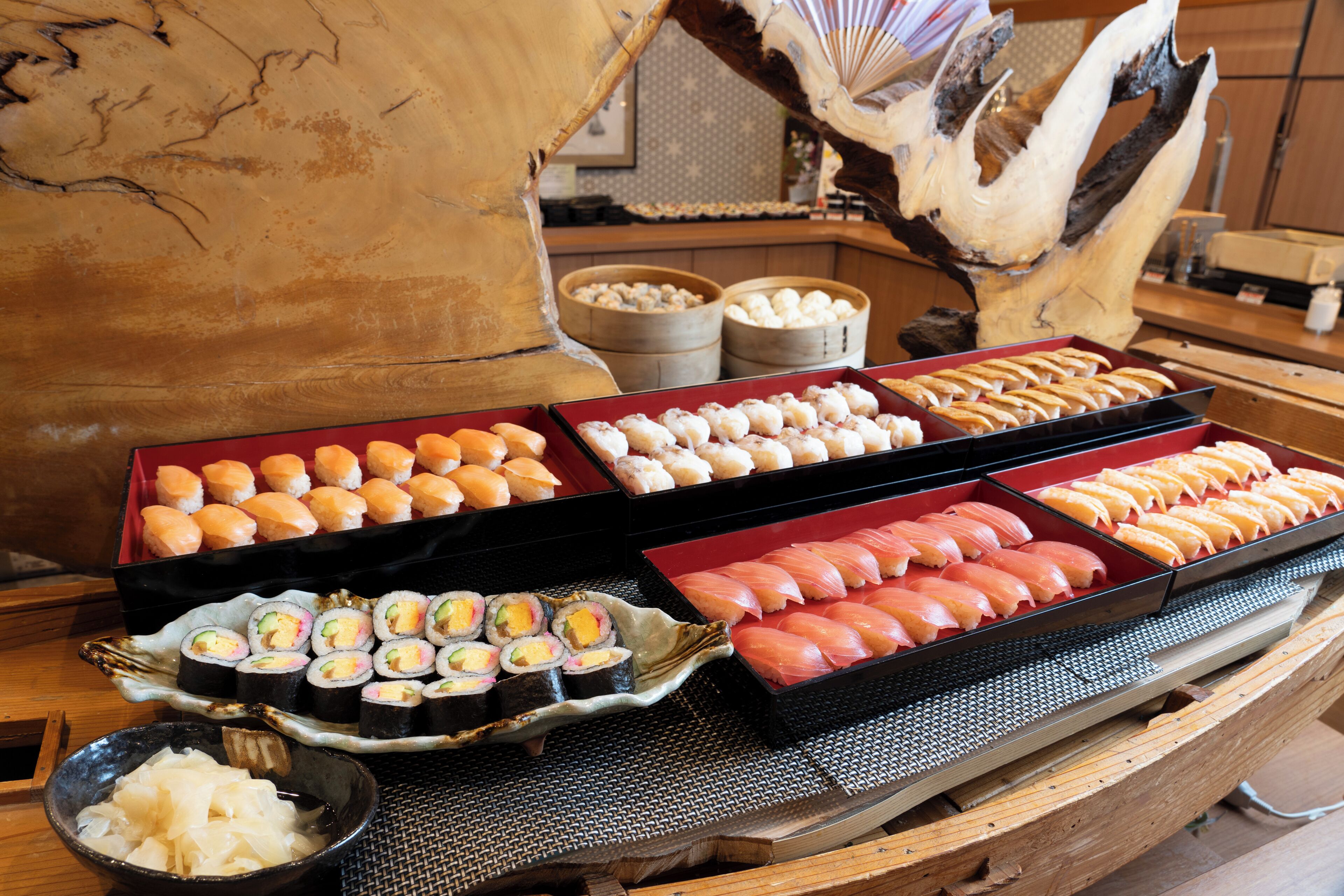 A sushi display with various types of sushi and other dishes.