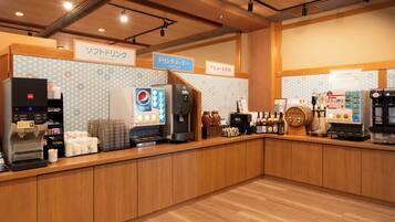Mostrador de una cafetería con varias máquinas de café y un refrigerador de Pepsi.
