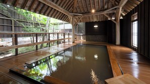Un bain de source chaude intérieur, doté d’un plancher en bois et d’une structure de plafond en bois.