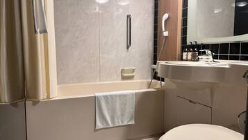 A bathroom with a bathtub, toilet, sink, and mirror.
