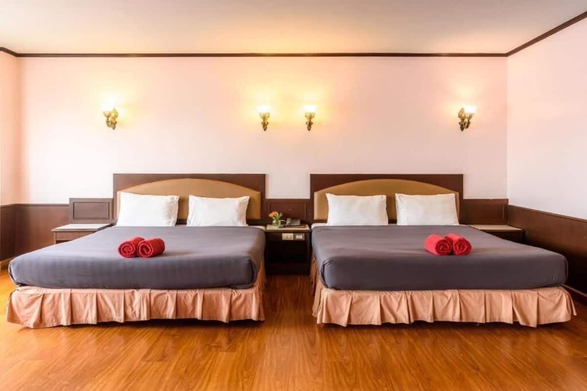 Ein Hotelzimmer mit zwei Betten, Holzboden und Wandleuchten.