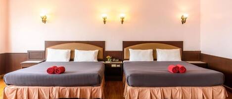 Quarto de hotel com duas camas, piso de madeira e luminárias fixadas na parede.