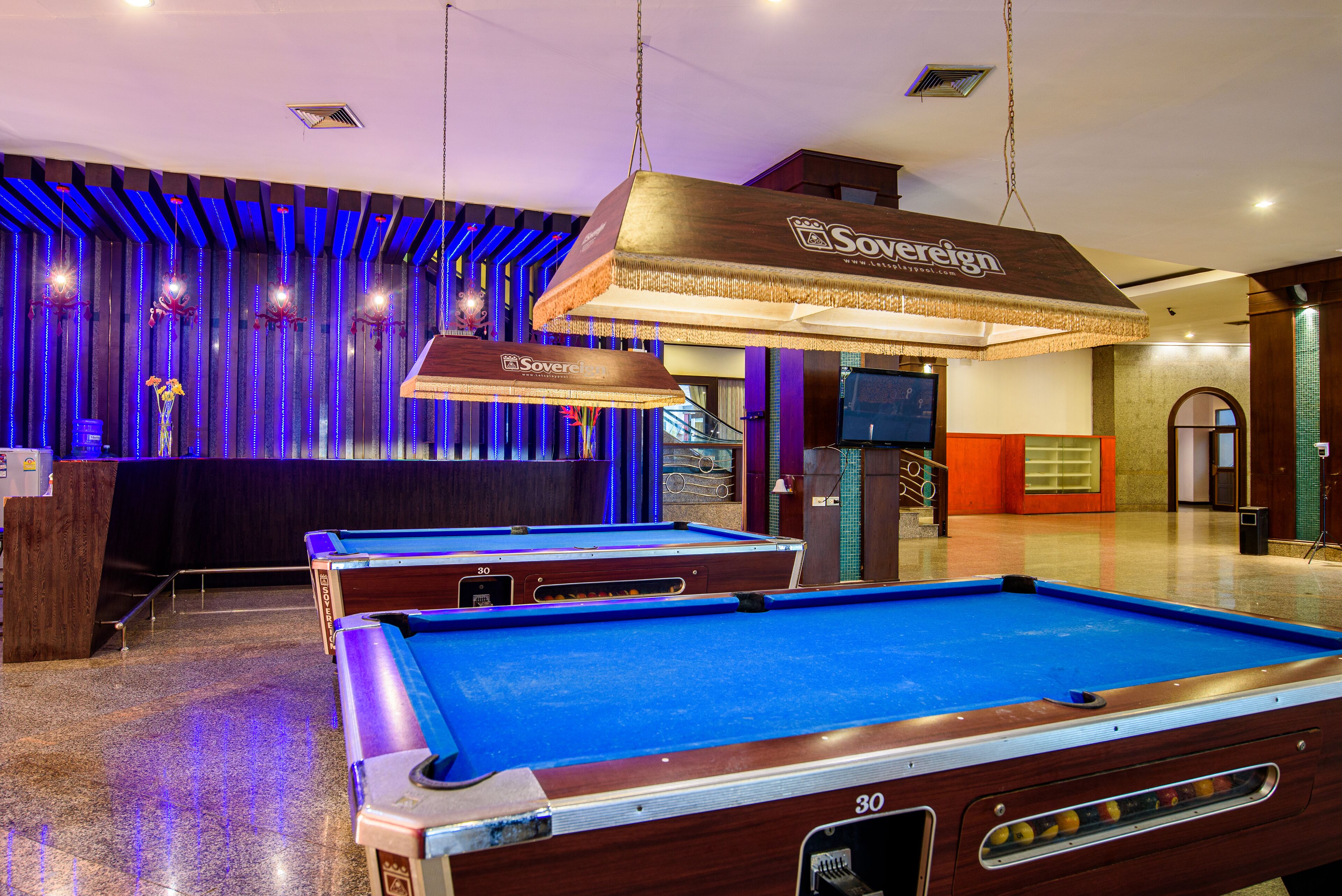 A pool table with a 'Sovereign' sign, a bar area, and a staircase leading to an upper level.