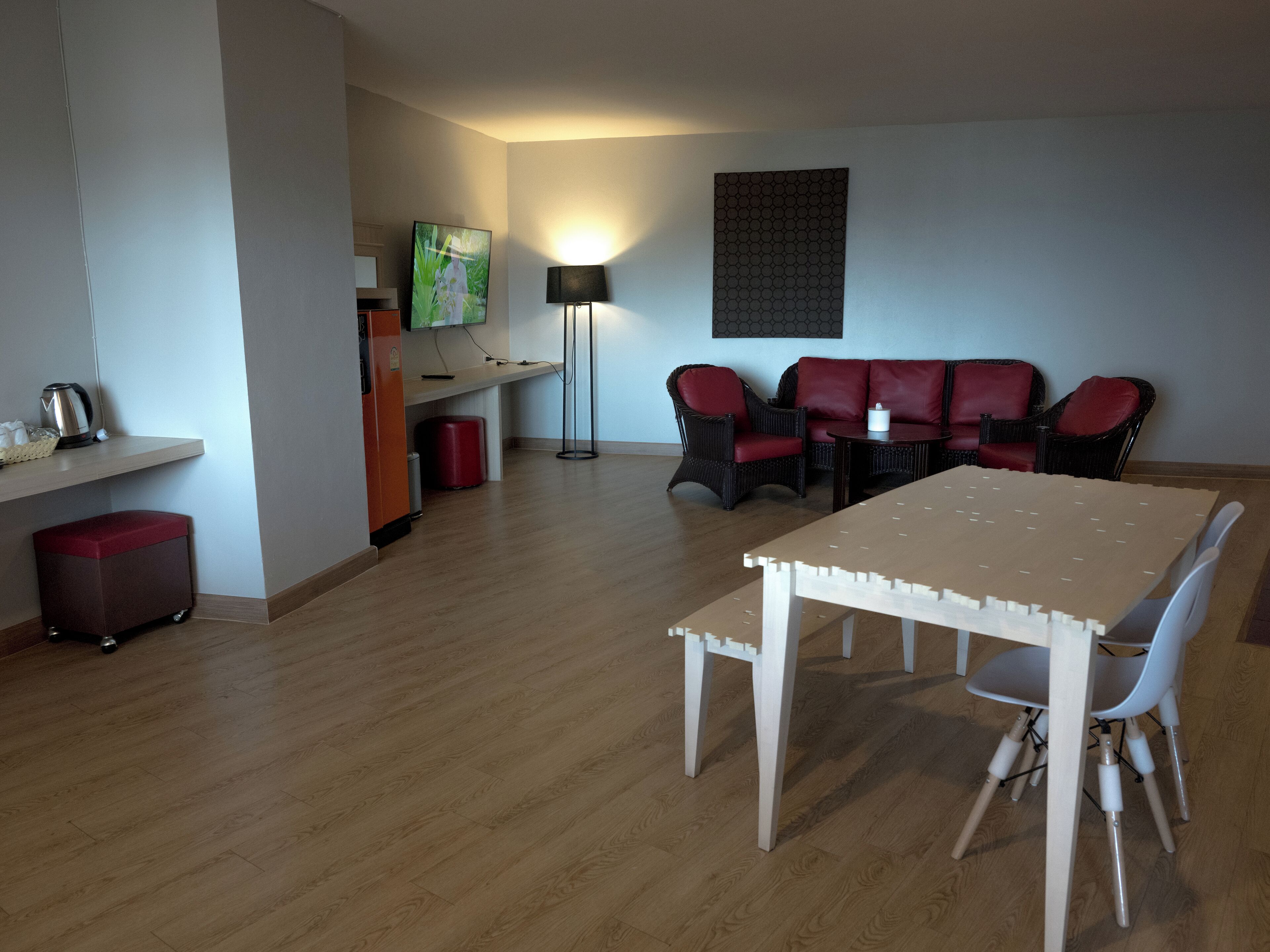 A modern living room with a dining table, chairs, a sofa set, a TV, and a lamp.