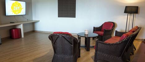 A modern living room with wicker furniture, a flat-screen TV, and a wall-mounted artwork.