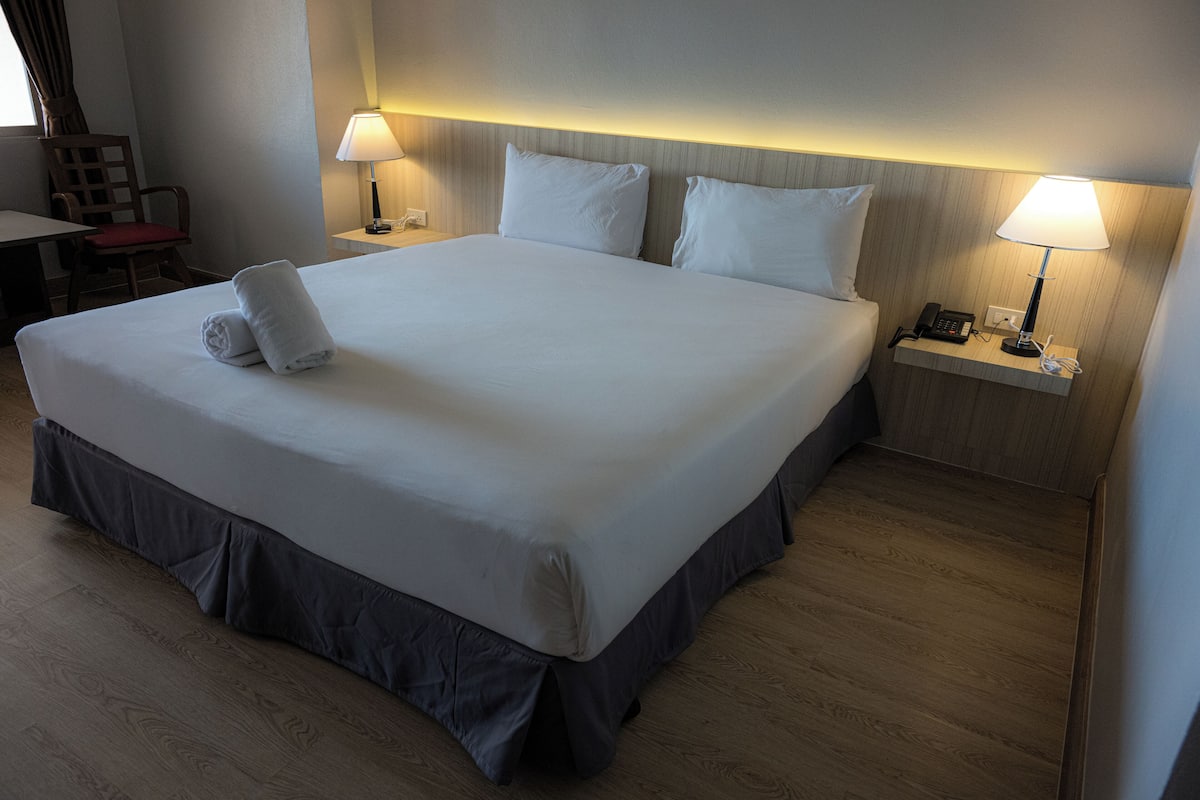 Ein großes Bett mit dunklem Bettvorhang, zwei Nachttischlampen und ein Telefon am Nachttisch.