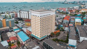 Ein Hochhaus-Hotel mit mehreren Etagen, umgeben von anderen Gebäuden und Blick auf das Meer.