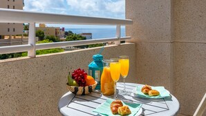 Ein Balkon mit einem Frühstückstisch, komplett mit Croissants, einer Obstschale und Orangensaftgläsern.