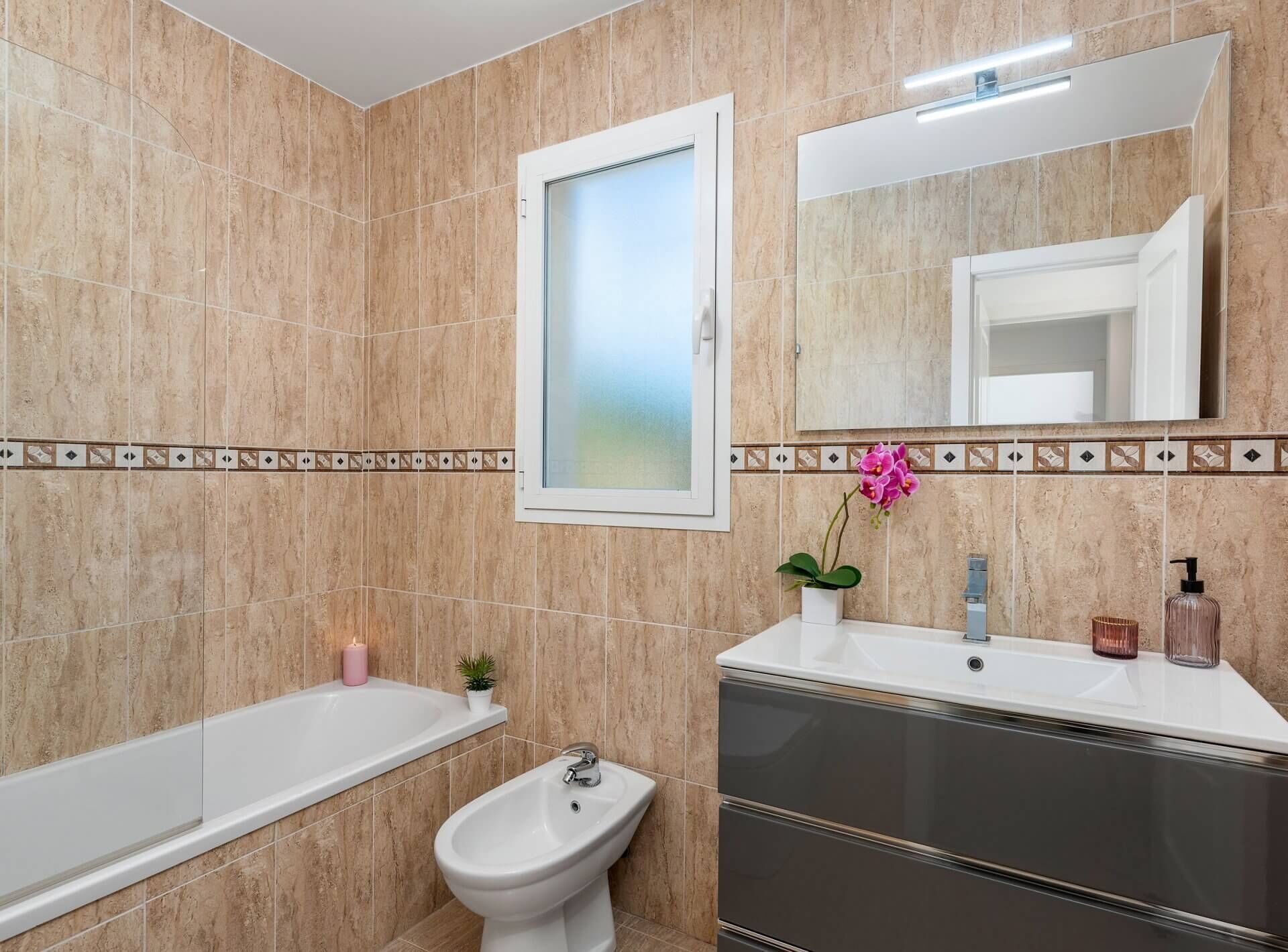 A modern bathroom with a bathtub, a bidet, a sink, and a mirror.