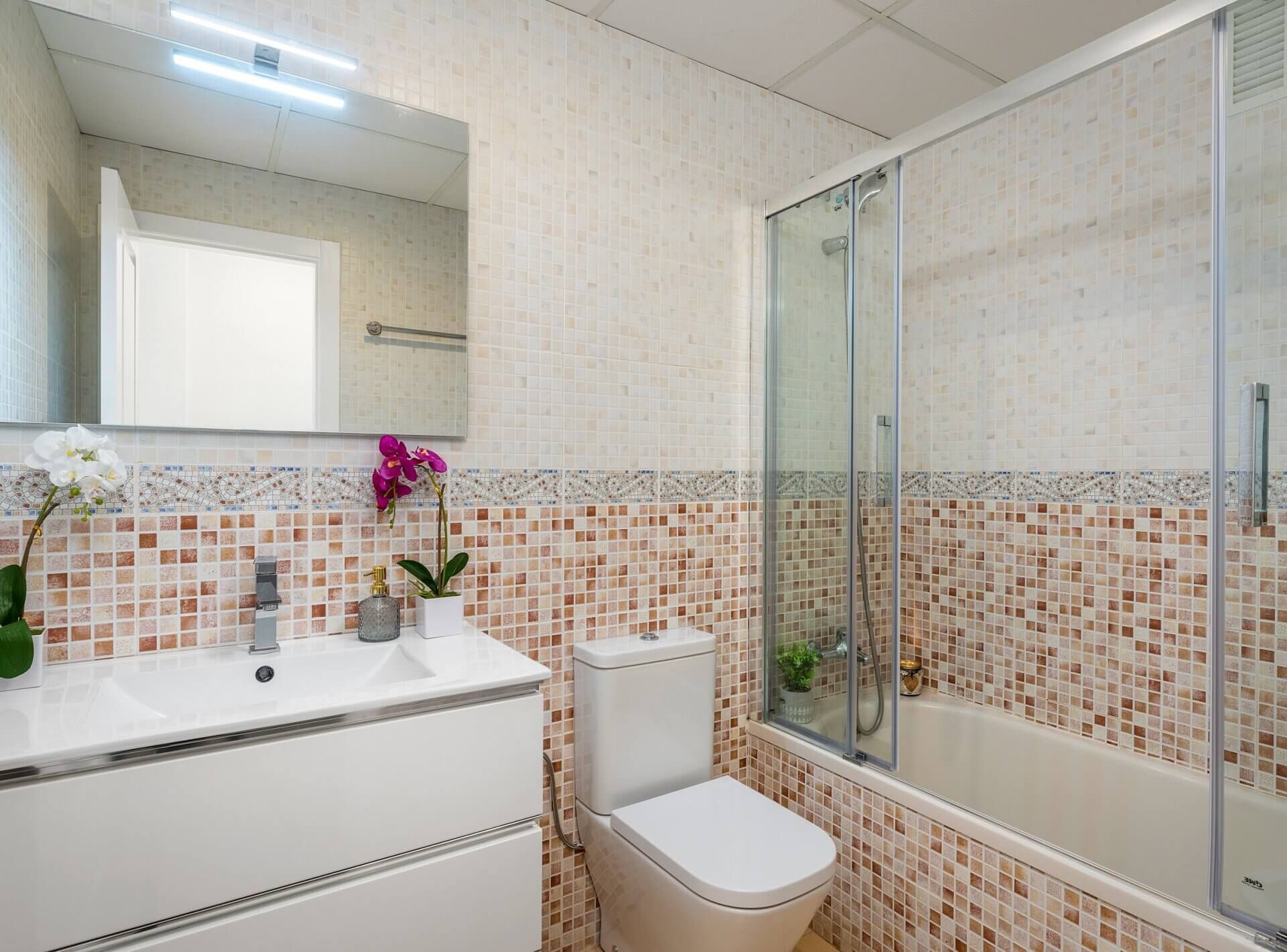 Une salle de bain avec un lavabo blanc, des toilettes et une douche à parois de verre.