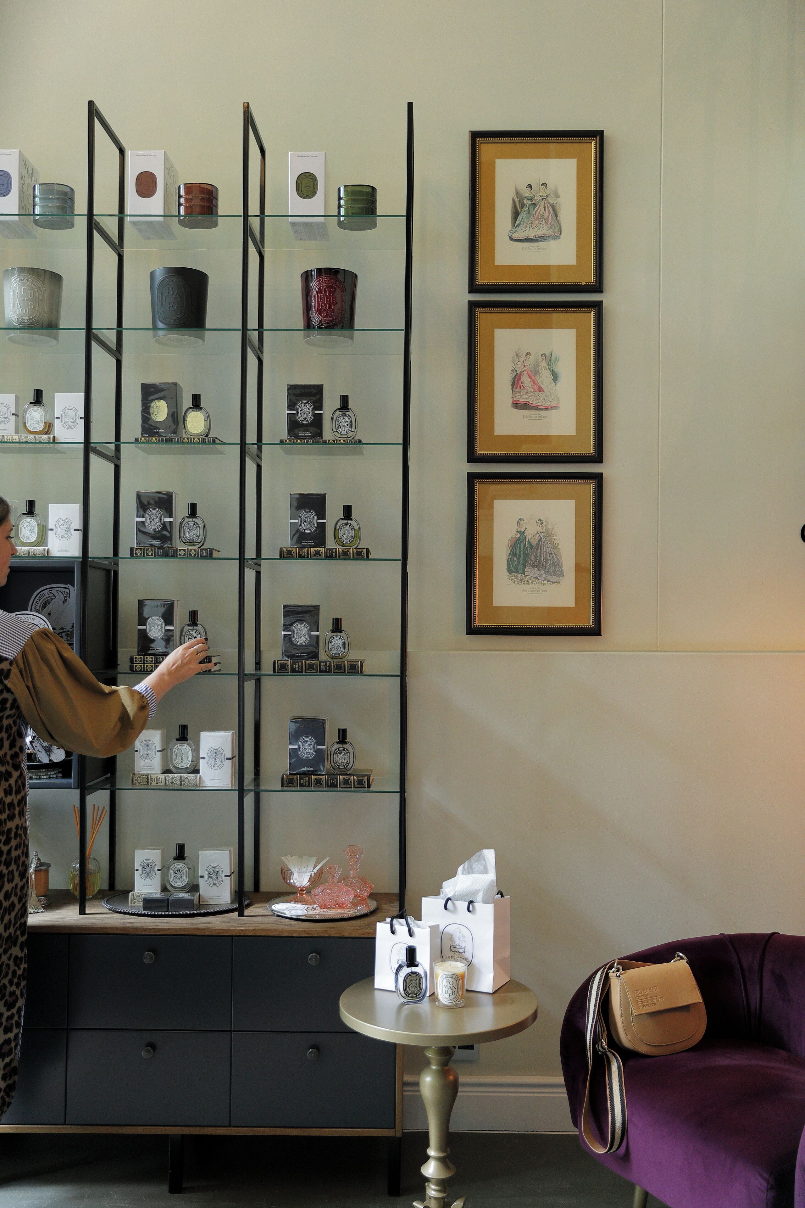 A person browsing a glass display of perfume bottles in a boutique setting.