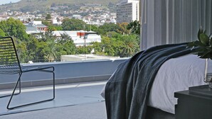A hotel room with a bed, a chair, a view of a mountain, and a cityscape. - Labotessa Luxury Boutique Hotel (Cape Town)