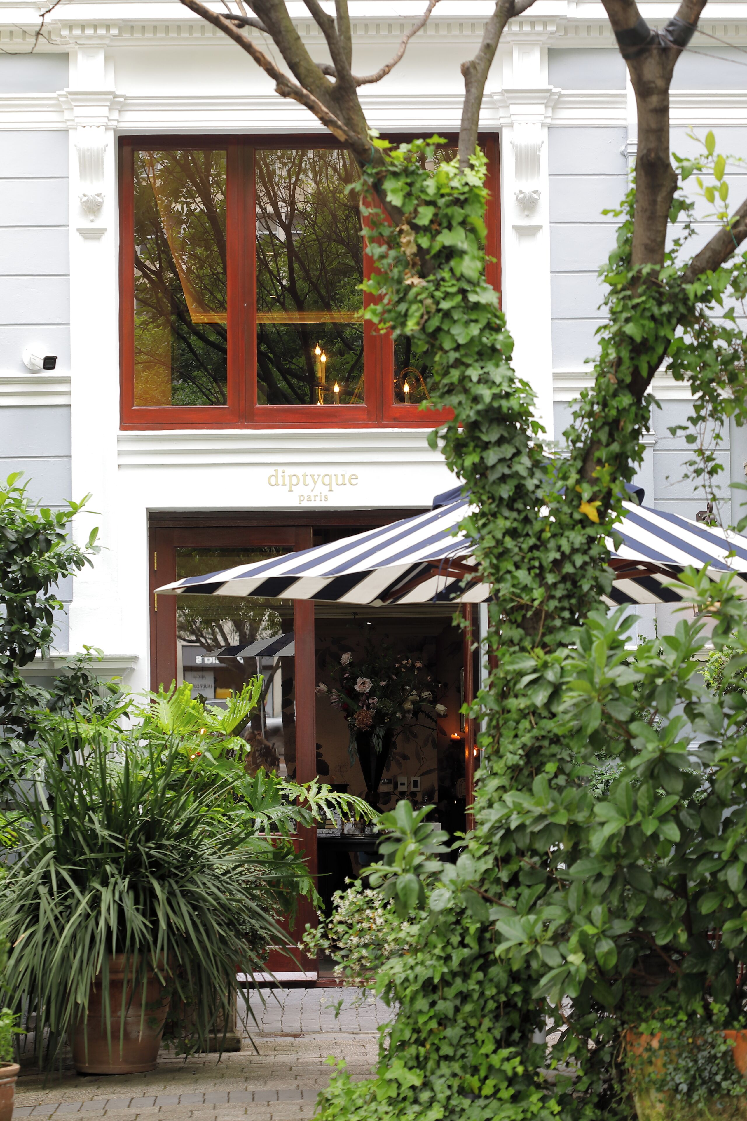 A building with a sign reading "diptyque paris" and a striped awning.