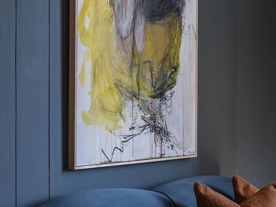 Um quarto com uma pintura abstrata grande na parede, um sofá azul e uma mesa de madeira.