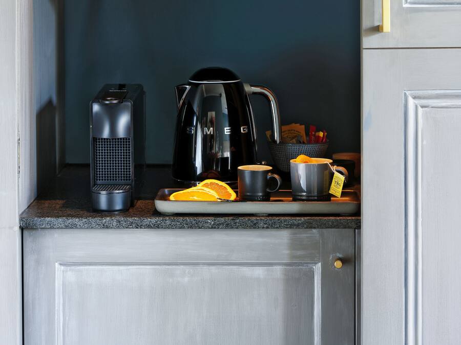 Eine Küchenarbeitsplatte mit einer Kaffeemaschine, einem Wasserkocher und einer Schale mit Orangenscheiben.