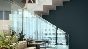 A modern staircase with glass railings, leading to a dining area with a table and chairs. - Labotessa Luxury Boutique Hotel (Cape Town)