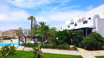 A resort with a swimming pool, lush greenery, and a white building with balconies.